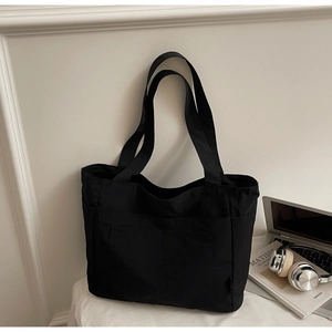 Detail der schwarzen Segeltuch-Tasche mit Vordertasche und gewebtem Etikett-Design
