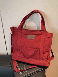 Large burgundy canvas tote bag with front pocket and adjustable shoulder strap