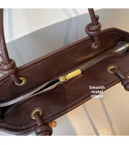 Vue détaillée du cuir grainé marron foncé et de la fermeture éclair dorée fluide