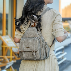 Detail of vintage soft leather backpack showing dual buckle straps and textured silver finish