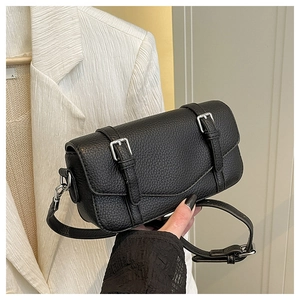Detalle de bolso bandolera negro de piel granulada con hebillas plateadas y solapa