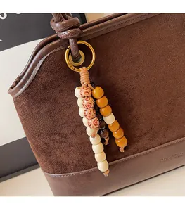 Détail du sac cabas vintage avec breloque en perles de bois et base en cuir poli