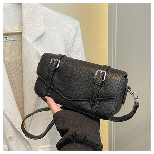 Detalle de bolso bandolera de cuero granulado negro con hebillas plateadas decorativas