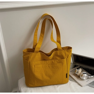 Detailansicht der gelben Canvas-Einkaufstasche mit Vordertaschen und Lifestyle-Zubehör