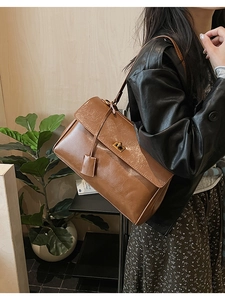Detail of vintage brown matte leather shoulder bag featuring a gold metal twist lock
