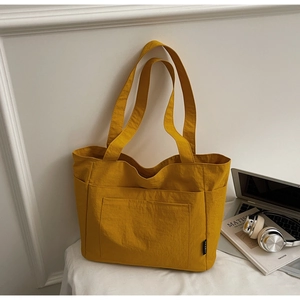 Gelbe Tragetasche mit Doppeltaschen und Laptop auf einem schlichten Schreibtisch