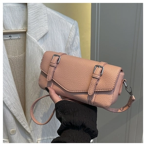 Detalle del bolso bandolera de cuero rosa claro con diseño de lichi y hebillas de metal dobles