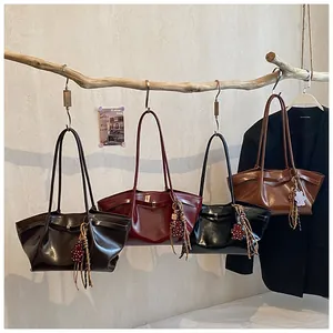 Detail of four glossy leather tote bags in various colors hanging on wooden branches