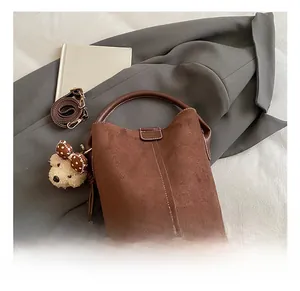 Details einer dunkelbraunen matten Beuteltasche mit Ziernaht, Gurt und Plüschanhänger