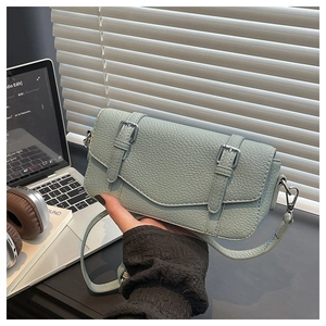 Detalle del bolso bandolera verde menta con textura de grano litchi y hebillas