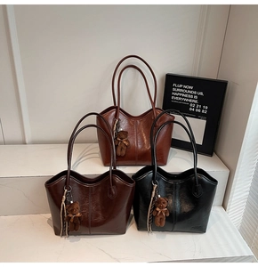 Detailed view of glossy patent leather tote bags in brown and black with plush bear charms