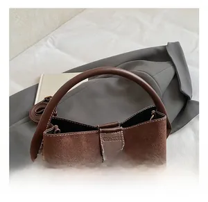 Detailansicht der braunen Wildleder-Beuteltasche mit Logo und gepunktetem Anhänger