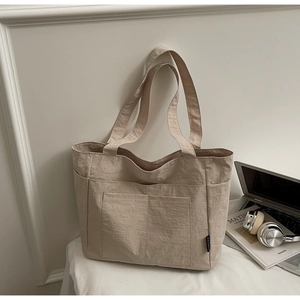 Details der beigen Nylon-Tragetasche mit mehreren Taschen und plissierter Textur
