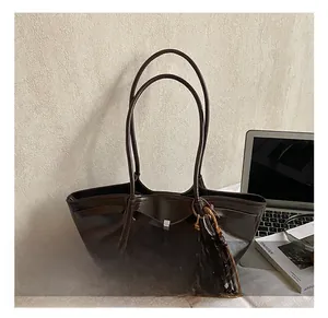 Detail of dark brown leather tote bag with stylish leopard print charm and metal buckle