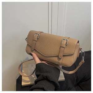 Detalle de bolso bandolera de cuero granulado caqui con hebillas plateadas y correa