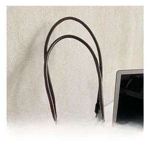 Detail of coffee brown tote bag handle showing high-gloss leather and neat stitching