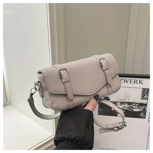 Detalle del bolso bandolera gris claro en cuero granulado con correas de hebilla doble