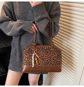 Dettaglio borsa tote con stampa leopardata, spalline annodate e ciondolo di perline