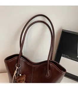 Detail of vintage dark brown tote bag with wavy rim, thin straps and plush bear charm