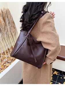 Detailed side view of large coffee brown tote bag with stylish ties on camel coat