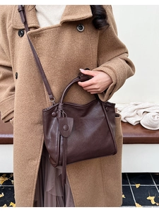 Detail of a dark brown vintage tote bag with decorative tassel and round top handle