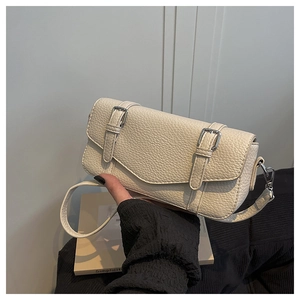 Detalle de bolso color crema en cuero con textura de lichi y hebillas metálicas plateadas