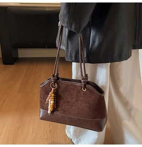 Dettaglio borsa tote vintage marrone scuro con patchwork scamosciato e ciondolo in legno