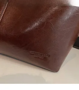 Close-up of vintage dark brown wax leather texture and embossed logo on tote bag