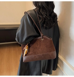 Dettaglio della borsa tote marrone vintage con nappa di perline e texture in pelle