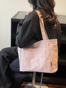 Rosa Tragetasche aus Nylon mit Knitteroptik und mehreren Taschen für den Alltag am Modell