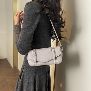Detalle de bolso de cuero rosa con hebillas plateadas sobre un vestido de punto texturizado