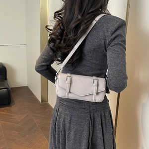 Detalle de bolso baguette de cuero granulado beige con doble hebilla y herrajes plateados