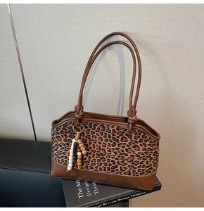 Dettaglio della borsa tote leopardata con nappa in legno su ecopelle marrone