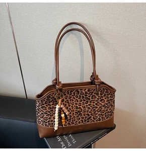 Dettaglio della borsa tote leopardata con finiture in pelle marrone e nappina di perline