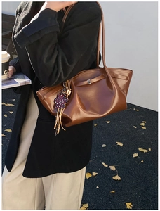 Detail of a brown tote bag with metal buckle and leopard print tassel on a shoulder strap