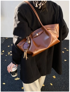 Detailed view of brown leather tote bag with stylish leopard print heart and tassel charm