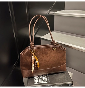 Dettaglio borsa tote marrone vintage con pannelli in camoscio e ciondolo con perline