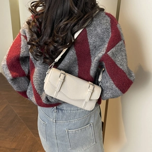 Detalle de bolso de hombro en piel granulada beige con correas decorativas de hebilla