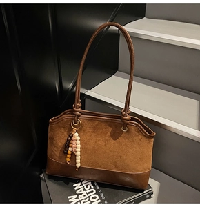 Dettaglio della borsa tote vintage marrone con ciondolo di perline e manico