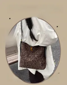 Detail of leopard print suede bucket bag with gold-tone twist lock and black strap