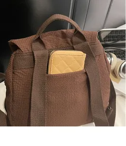 Detail of durable front pocket on brown textured backpack showing storage capacity