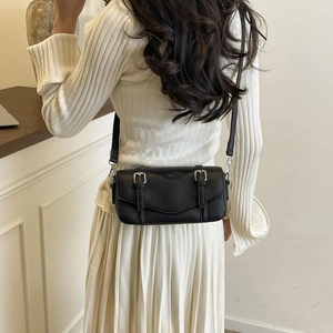 Vista trasera de una modelo con bolso bandolera de cuero negro y hebillas plateadas