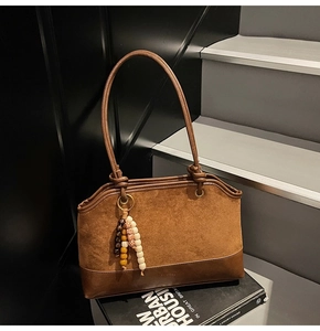 Borsa tote vintage marrone con texture scamosciata e ciondolo etnico su una scala