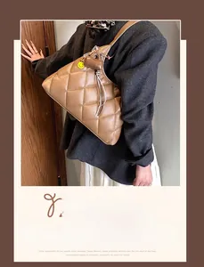 Detail of a brown quilted shoulder bag featuring a yellow smiley face charm and leather texture