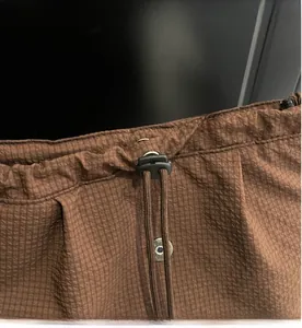Detail of brown checkered backpack with adjustable drawstring closure and black buckle