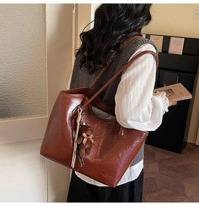 Detail of oil wax leather tote bag with cute bear charm and golden ribbon accent