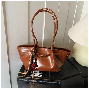 Detailed view of brown glossy leather tote bag with leopard bear and tassel charm detail