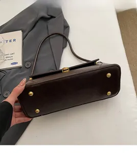 Close-up of dark brown leather bag bottom with four golden protective metal studs