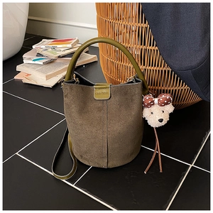 Detail der olivgrünen Wildleder-Eimertasche mit Ledergriff und Teddybär-Anhänger
