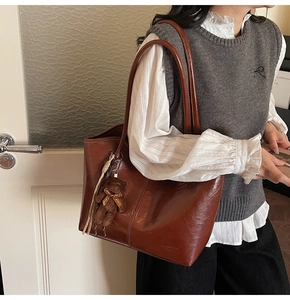 Detail of retro reddish-brown tote bag with shiny finish and cute teddy bear charm